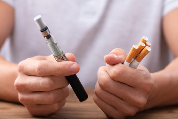 Man Holding Vape And Cigarette